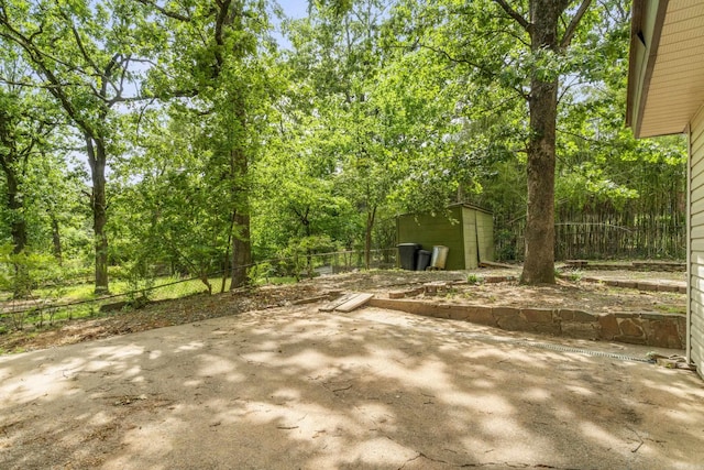 view of yard with a storage shed, fence, an outdoor structure, and a patio area