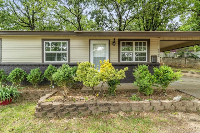 view of front of house featuring brick siding, fence, and an attached carport