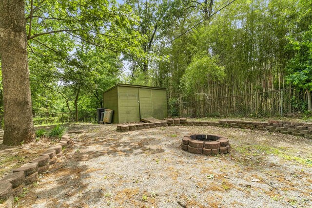 view of yard with a storage unit, an outdoor fire pit, fence, and an outbuilding