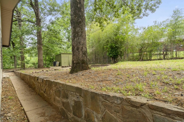 view of yard featuring fence, an outdoor structure, and a storage unit