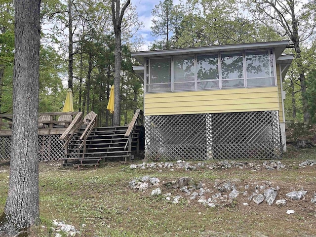 exterior space featuring a wooden deck, stairs, and a sunroom