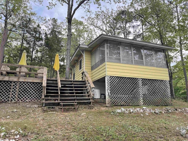 exterior space with a wooden deck, a sunroom, and stairway