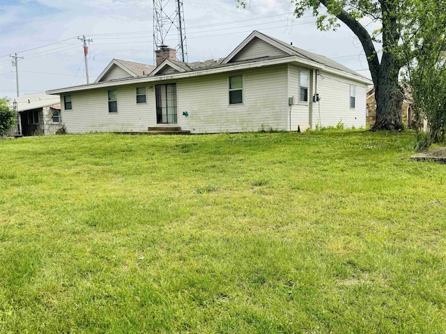 rear view of property featuring a lawn and a chimney