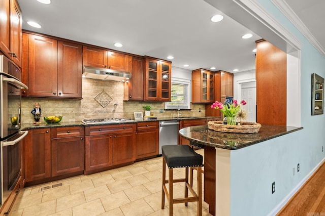 416 Ivory Dr, Little Rock, AR 72205 - kitchen with decorative backsplash, under cabinet range hood, a sink, dark stone countertops, and appliances with stainless steel finishes