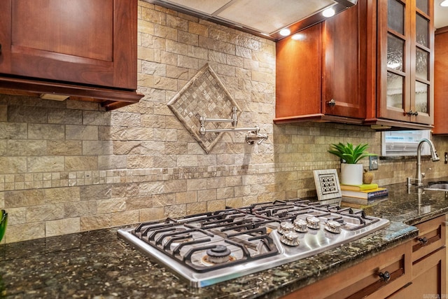 416 Ivory Dr, Little Rock, AR 72205 - kitchen with glass insert cabinets, dark stone counters, wall chimney exhaust hood, a sink, and stainless steel gas stovetop