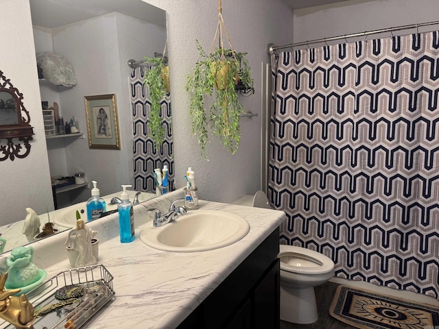 bathroom featuring toilet, a textured wall, curtained shower, and vanity