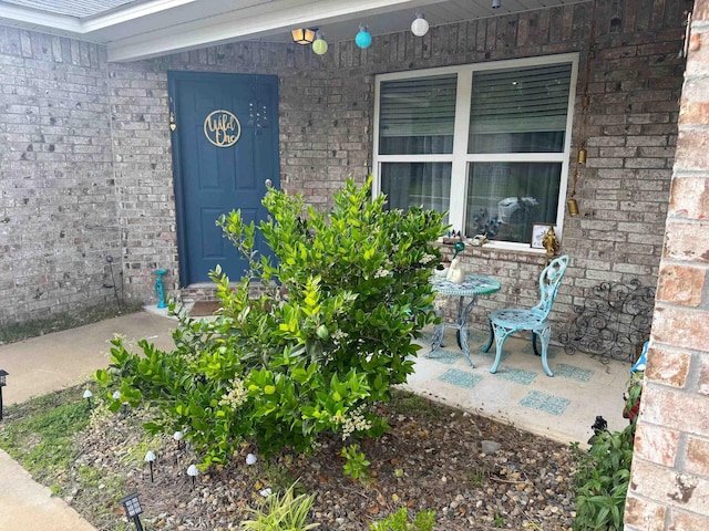 view of exterior entry featuring brick siding and covered porch