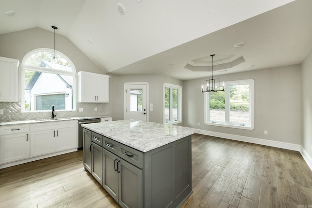 kitchen with a healthy amount of sunlight, a sink, gray cabinetry, white cabinets, and a notable chandelier