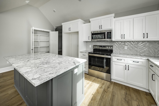 kitchen featuring light stone counters, decorative backsplash, wood finished floors, and stainless steel appliances