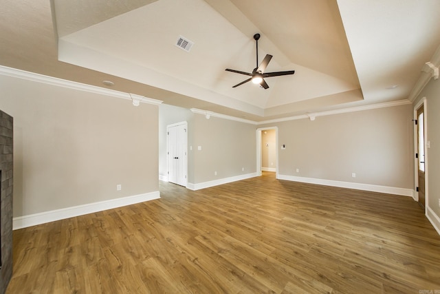 unfurnished living room featuring ceiling fan, a tray ceiling, wood finished floors, and visible vents