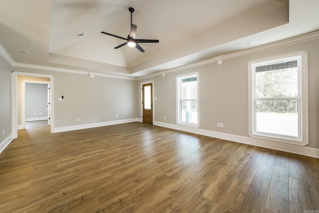 empty room with visible vents, wood finished floors, baseboards, a raised ceiling, and a ceiling fan