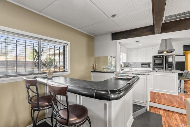7510 Briarwood Dr, Little Rock, AR 72205 - kitchen with a peninsula, island range hood, light wood-type flooring, white cabinets, and tasteful backsplash
