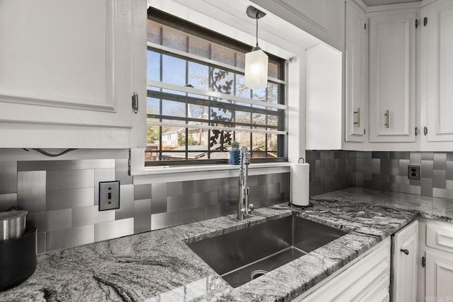 7510 Briarwood Dr, Little Rock, AR 72205 - kitchen with pendant lighting, white cabinetry, tasteful backsplash, light stone counters, and a sink