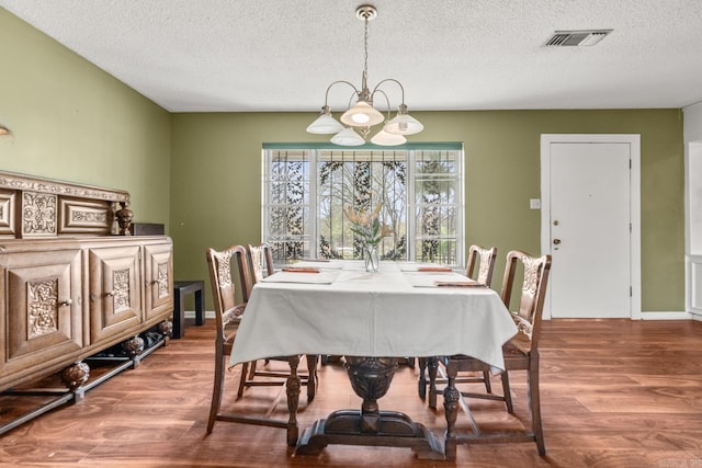 7510 Briarwood Dr, Little Rock, AR 72205 - dining area featuring visible vents, a textured ceiling, wood finished floors, and a chandelier
