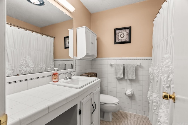 7510 Briarwood Dr, Little Rock, AR 72205 - full bathroom featuring tile patterned flooring, vanity, toilet, tile walls, and a wainscoted wall