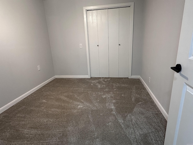 unfurnished bedroom featuring carpet floors, baseboards, and a closet