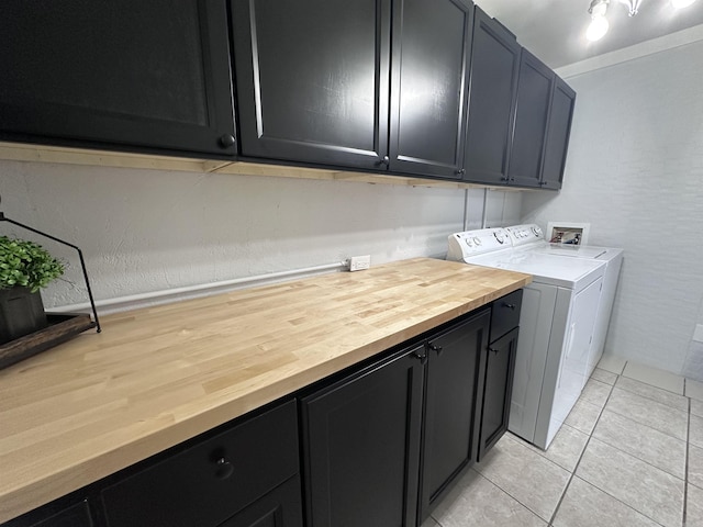 washroom featuring washer and clothes dryer, cabinet space, and light tile patterned floors