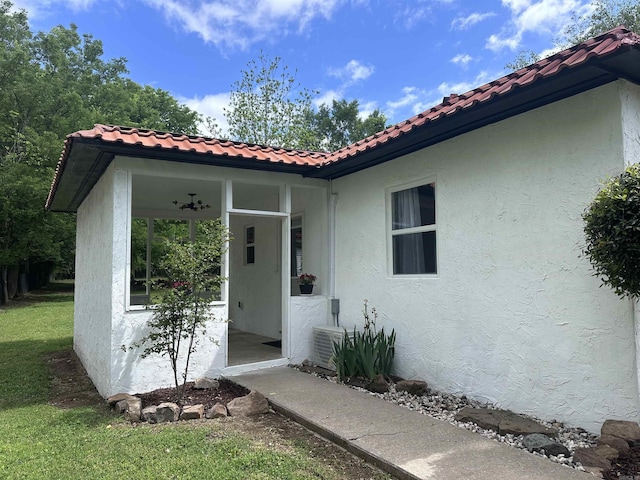 doorway to property featuring a lawn, stucco siding, and a tile roof