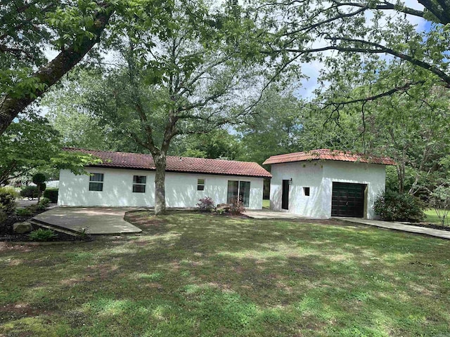 view of front of home featuring a garage, an outdoor structure, stucco siding, and a tiled roof