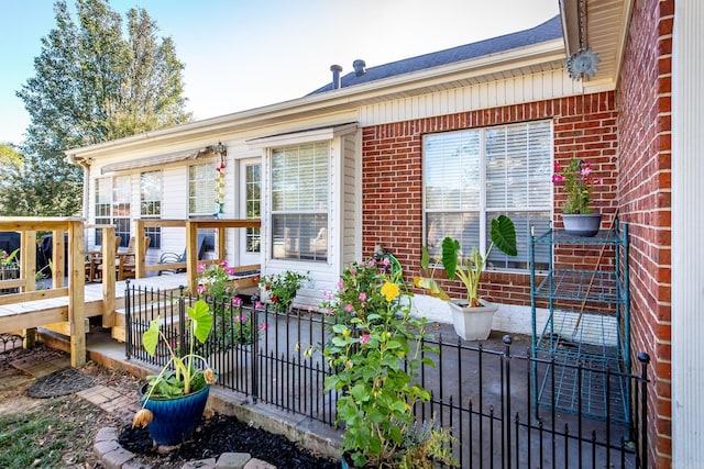 exterior space featuring fence, a wooden deck, and brick siding