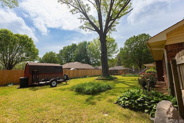 view of yard featuring an outdoor structure, a fenced backyard, and a shed