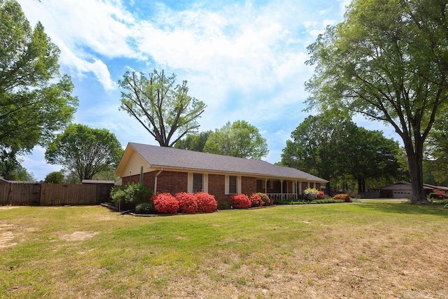 view of front of house with brick siding, fence, and a front lawn