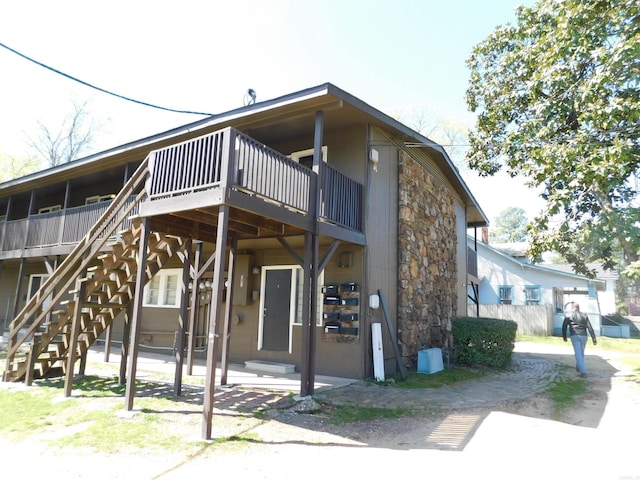 view of front of house with a deck, stairs, and stone siding