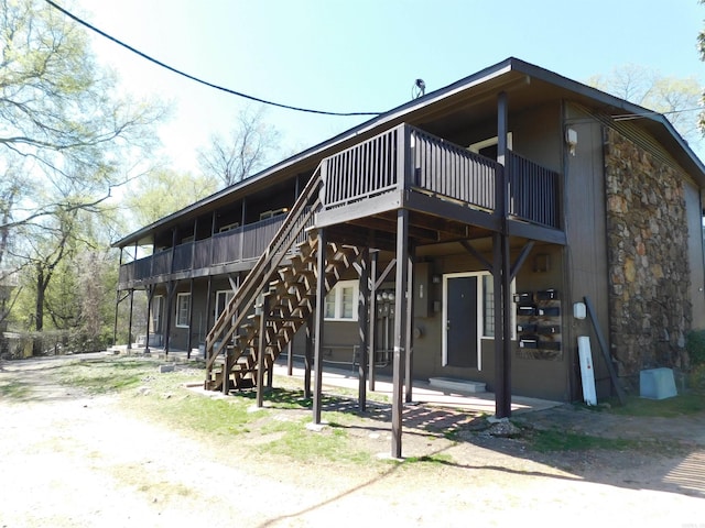 back of property with a wooden deck, stairs, and stone siding