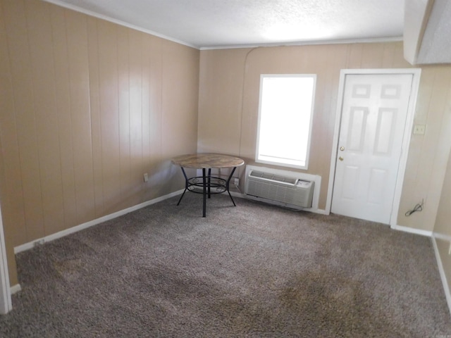 carpeted empty room with crown molding, baseboards, an AC wall unit, and wood walls