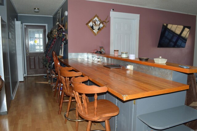 bar with ornamental molding and wood finished floors