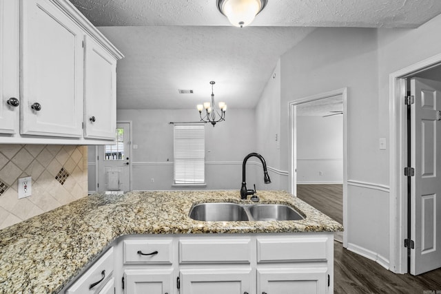 kitchen with a textured ceiling, white cabinetry, a sink, dark wood finished floors, and backsplash