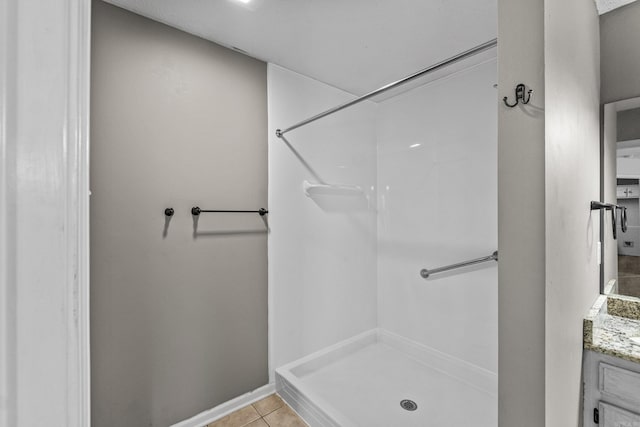 bathroom with vanity, tile patterned flooring, baseboards, and a shower stall