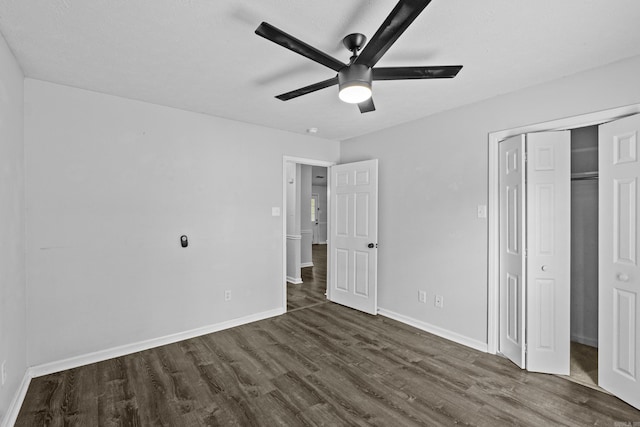 unfurnished bedroom with dark wood-type flooring, a ceiling fan, baseboards, and a closet