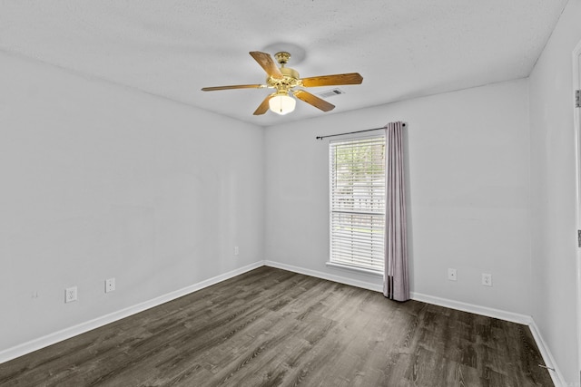 spare room featuring a textured ceiling, a ceiling fan, baseboards, dark wood-type flooring, and visible vents