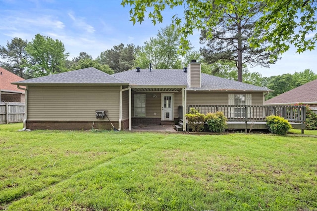 rear view of property with a lawn, roof with shingles, fence, and a chimney