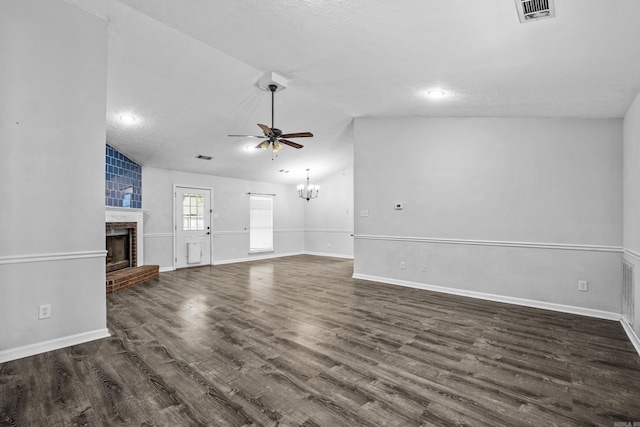 unfurnished living room with visible vents, a fireplace, ceiling fan with notable chandelier, dark wood-style floors, and lofted ceiling