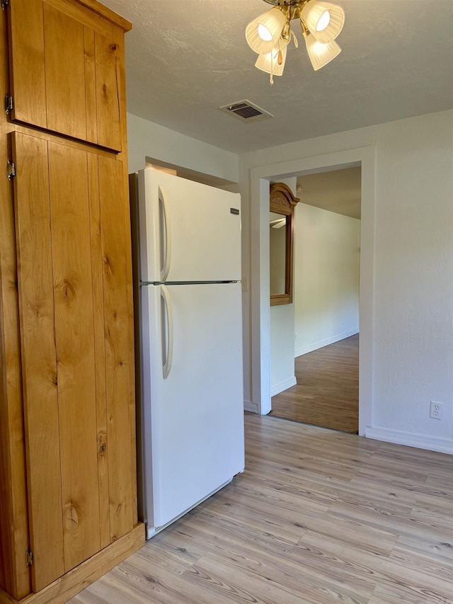 805 S St, Heber Springs, AR 72543 - kitchen with visible vents, freestanding refrigerator, baseboards, brown cabinets, and light wood finished floors