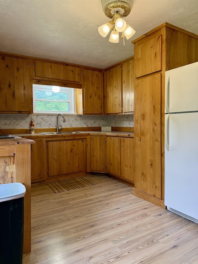 805 S St, Heber Springs, AR 72543 - kitchen featuring decorative backsplash, brown cabinets, a sink, freestanding refrigerator, and light wood-style flooring