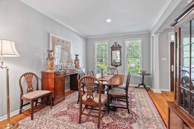 dining room featuring baseboards, ornamental molding, ornate columns, and light wood-style flooring
