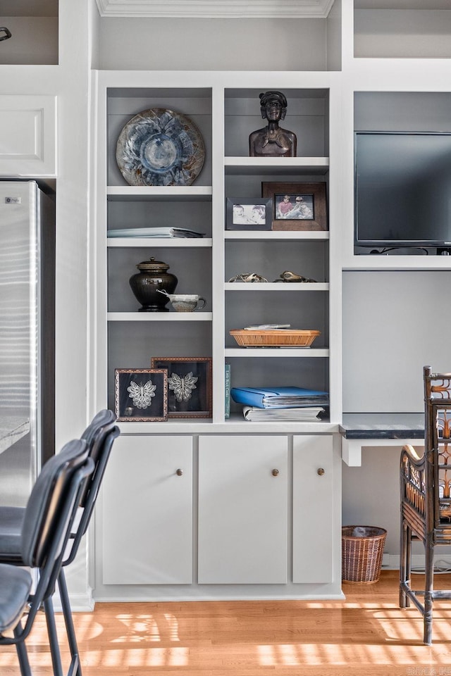 interior space with crown molding, freestanding refrigerator, light wood finished floors, and built in shelves