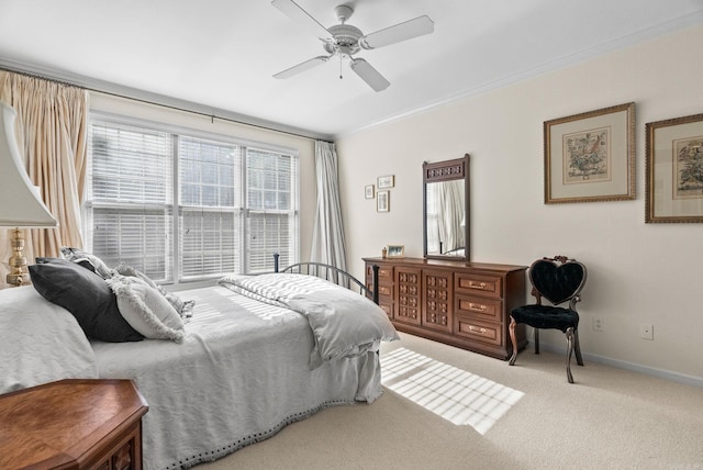 carpeted bedroom with crown molding, baseboards, and a ceiling fan