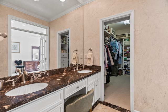 bathroom with a sink, a textured wall, double vanity, and a spacious closet