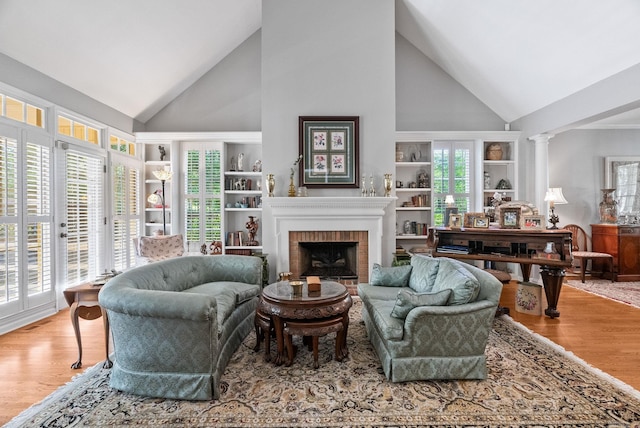 living area featuring high vaulted ceiling, a fireplace, and wood finished floors