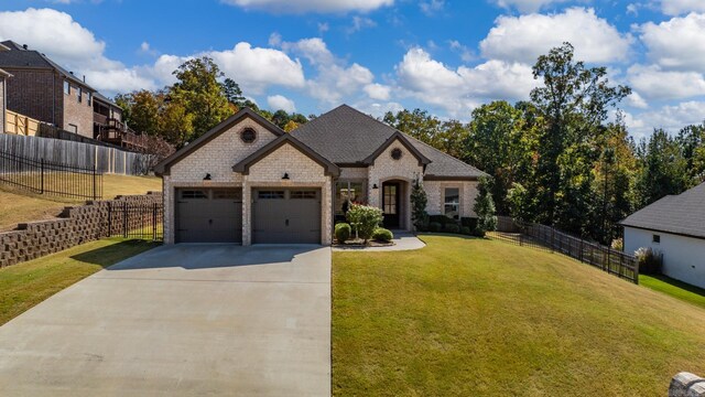 french country style house with a garage, a front lawn, fence, brick siding, and driveway