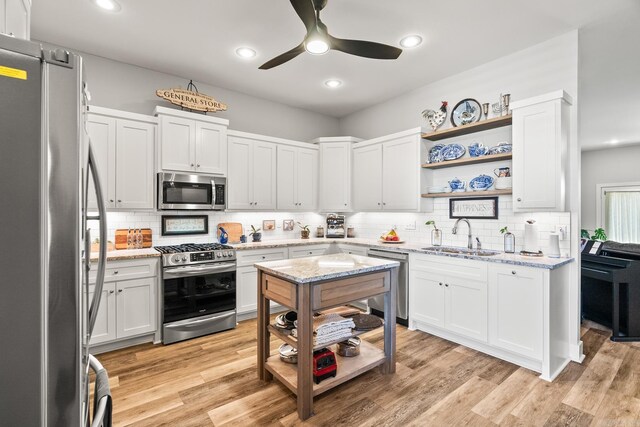 kitchen featuring open shelves, appliances with stainless steel finishes, decorative backsplash, and a sink