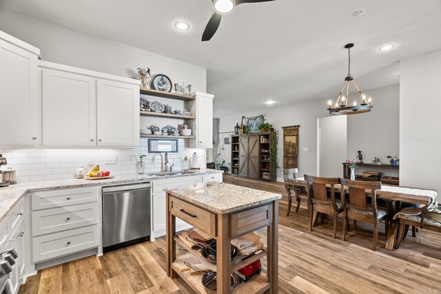 kitchen featuring backsplash, open shelves, stainless steel dishwasher, a sink, and ceiling fan with notable chandelier