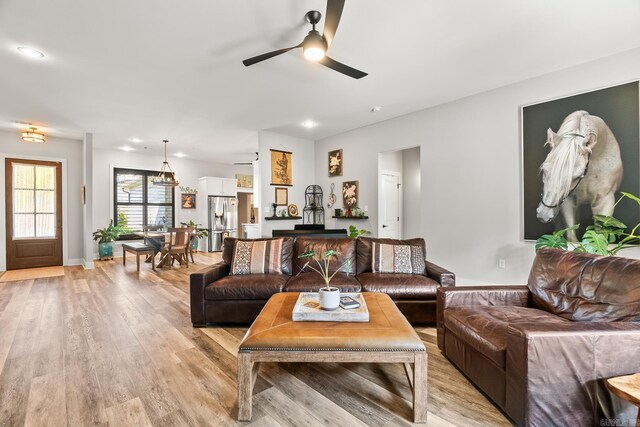 living room featuring baseboards, a ceiling fan, recessed lighting, and light wood-style flooring