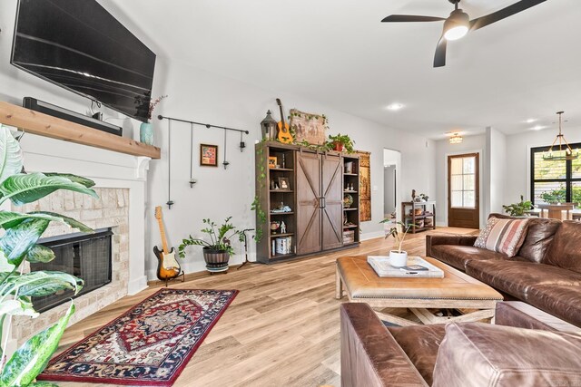 living area with ceiling fan, baseboards, light wood finished floors, and a fireplace