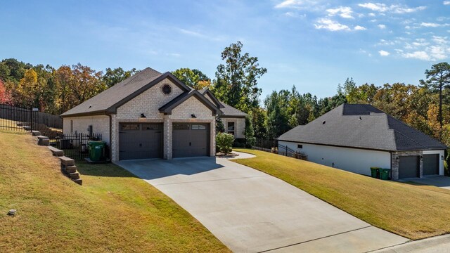view of side of home with fence, an attached garage, stone siding, a yard, and driveway