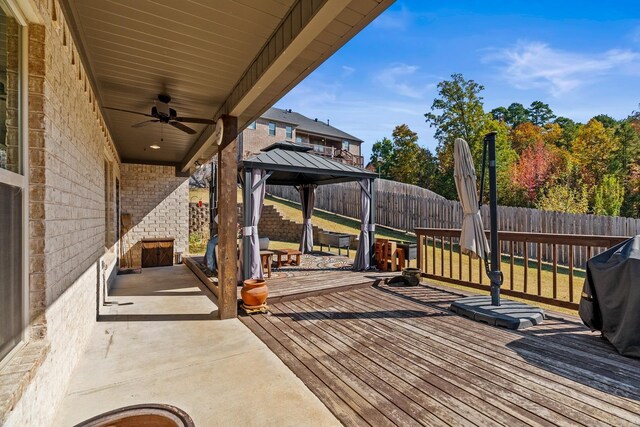 wooden terrace featuring a fenced backyard, a ceiling fan, and a gazebo